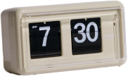 A beige flip clock resting on a stack of books