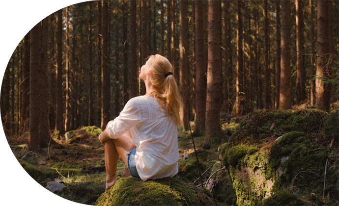 Woman sitting peacefully in a sunlit forest