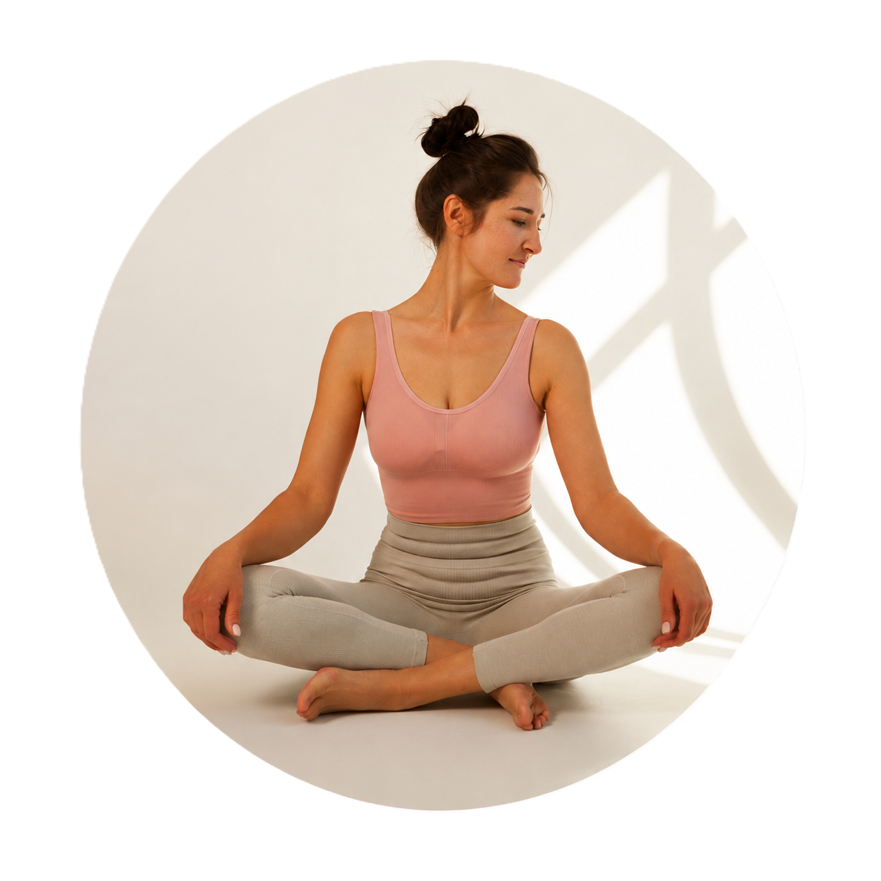 Woman sitting cross-legged in a sunlit yoga studio